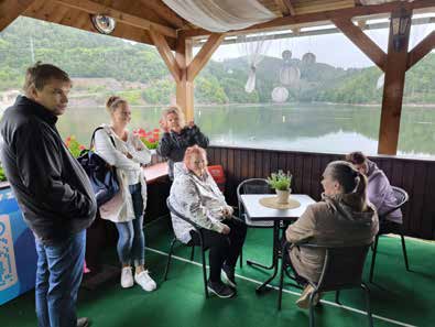 Auf dem überdachten Deck des Ausflugsboots stehen und sitzen die Ausflügler, im Hintergrund der See.